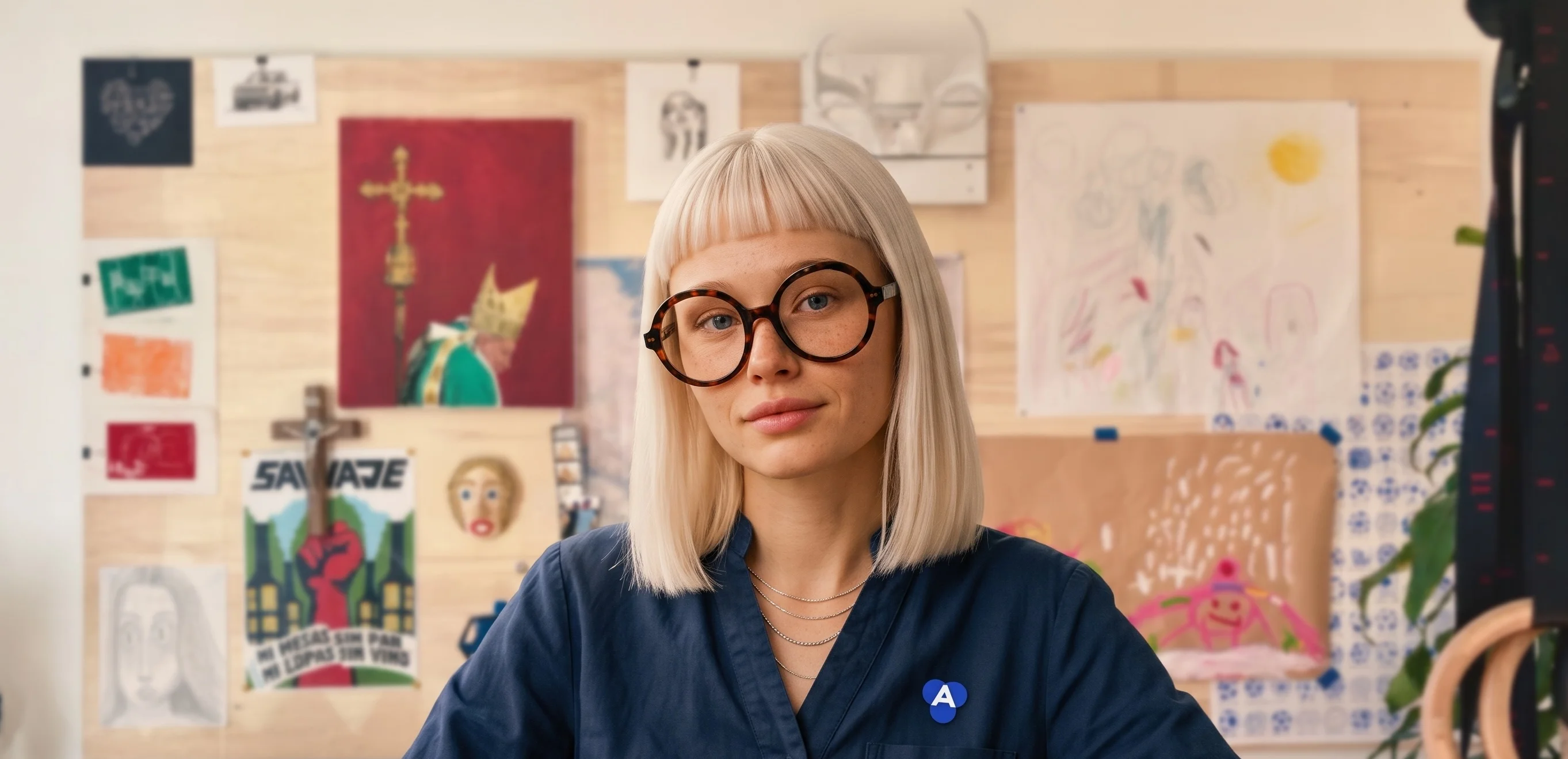 A person wearing glasses and a navy shirt with an answer.cloud pin.
